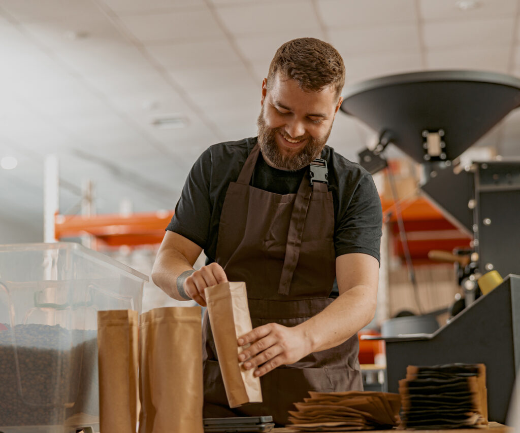 A man pouring coffee beans into a bag for his coffee brand
