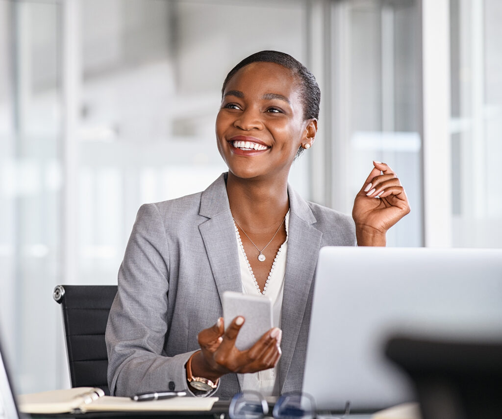 Woman smiling at her desk, prioritising her mental health